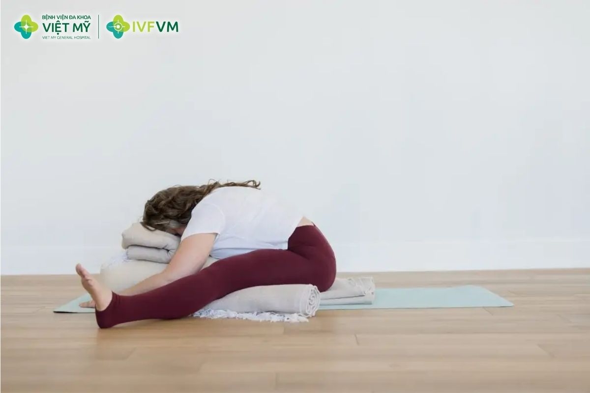 Tư thế ngồi gập người chân dang rộng có gối đỡ hỗ trợ thư giãn vùng hông, đùi trong và lưng dưới